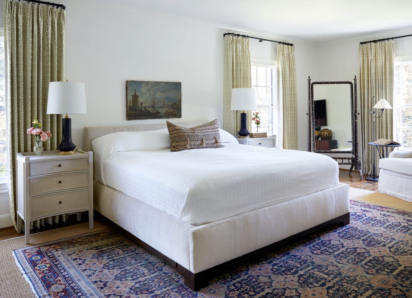 Treasures in this bedroom include an antique textile pillow, 18th-century Italian landscape painting, a vintage bamboo mirror and an antique Agra rug.