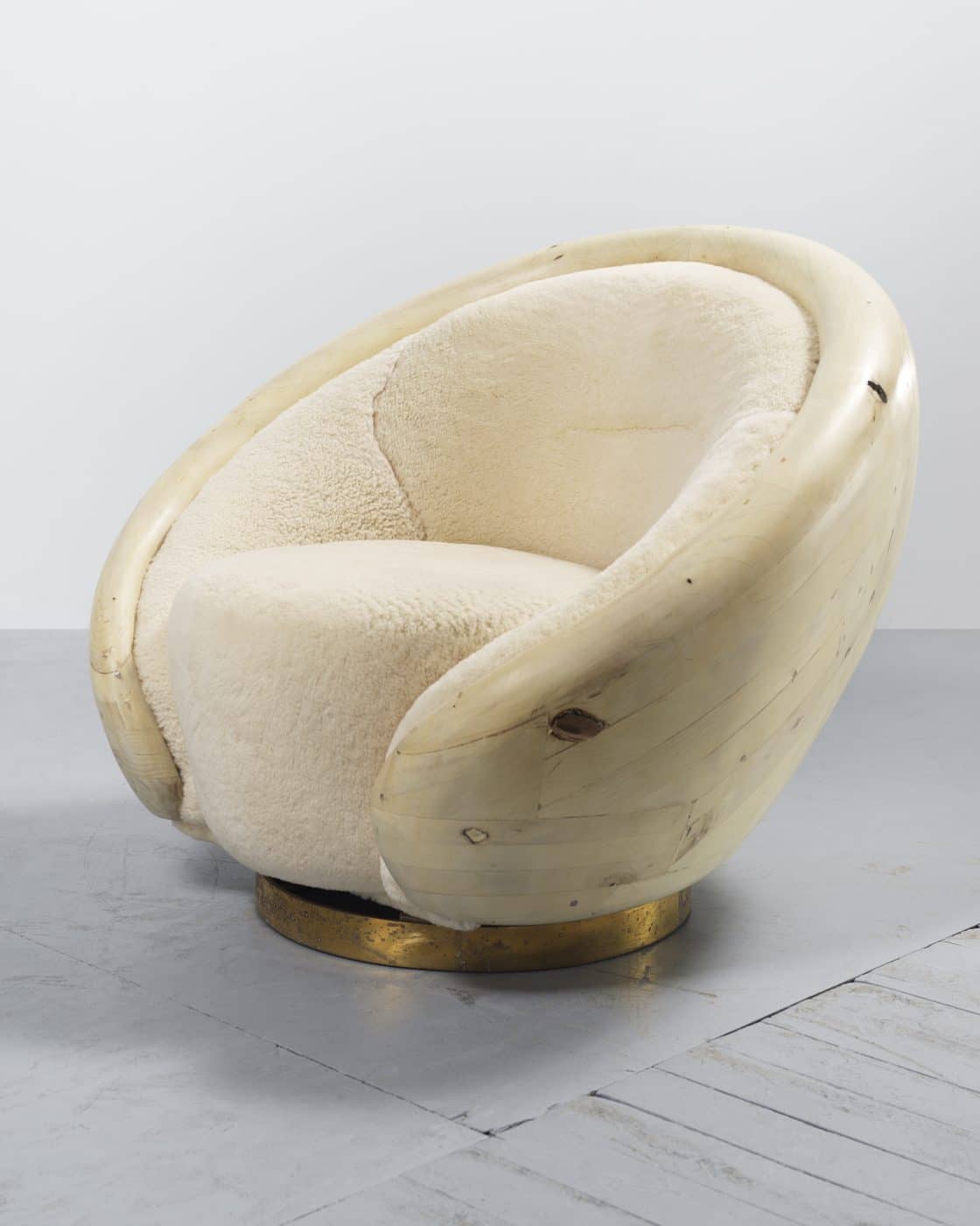 Rogan Gregory's Brioche chair, with ivory shearling upholstery, a wood back, and a bronze swivel base