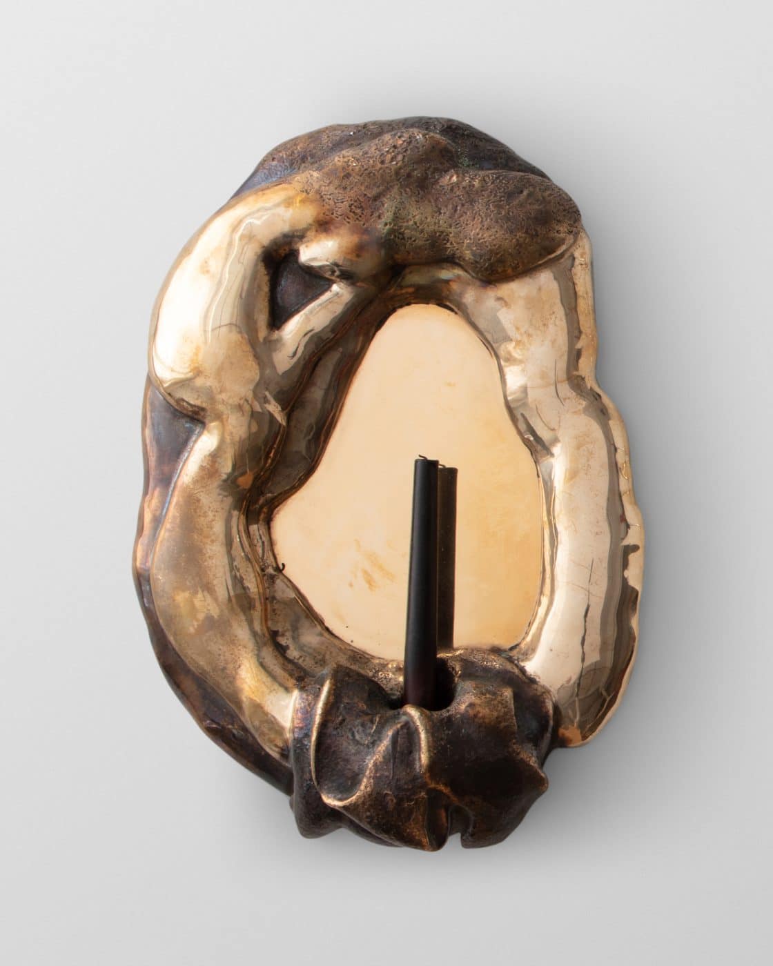 A Rogan Gregory mirror in bronze and glass that also acts as a sconce, holding a single candle