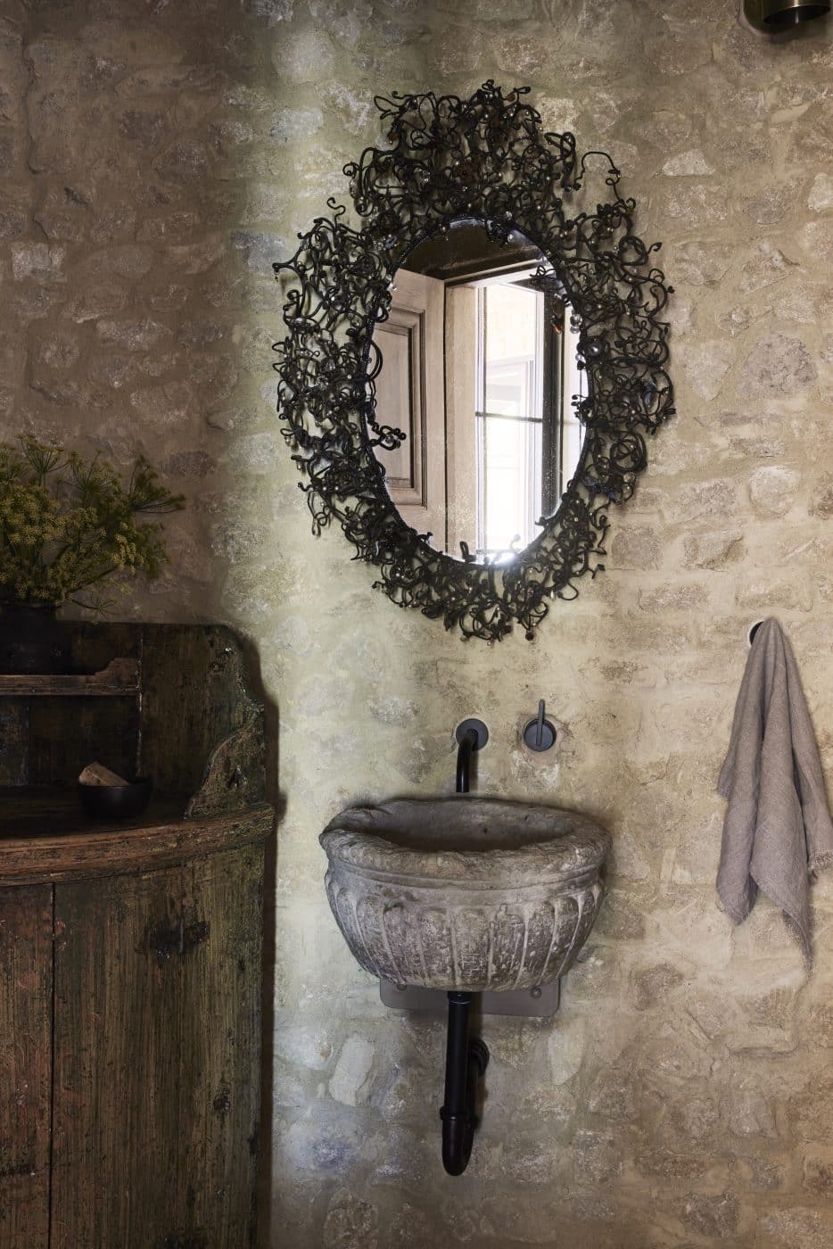 An antique French mirror and a rustic 18th-century Swedish sideboard in a powder room