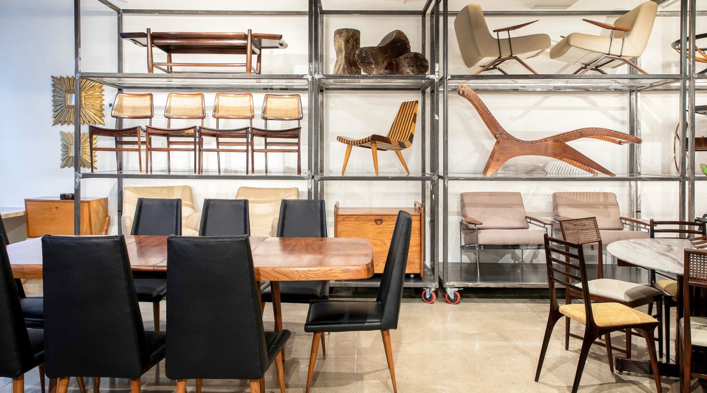 A variety of Brazilian modern furniture displayed on floor-to-ceiling metal shelves in the Found Collectibles showroom