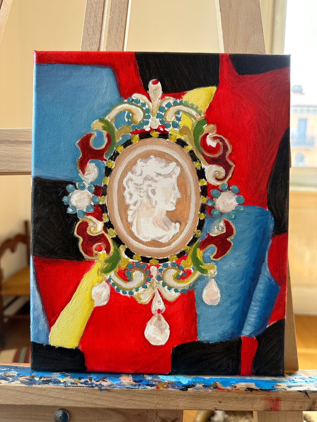 Painting of a 19th-century Charles Duron cameo brooch in a colorful enamel setting against a patterned Prada shirt in black, blue, red and yellow