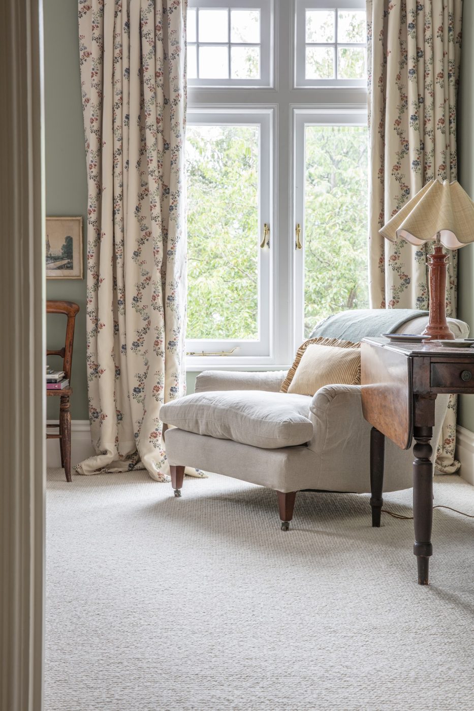 A large chair covered in natural-colored fabric in the main bedroom of Louise Roe's London home