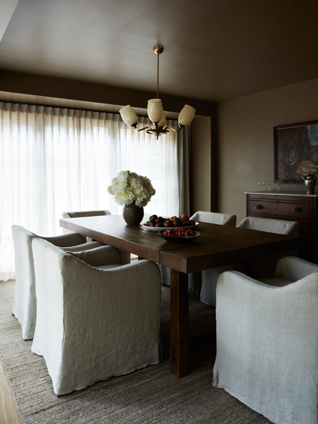beige slip-covered arm chairs around sold wood doning table in dining room of interior designer Molly Beth Kidd's Oregon home