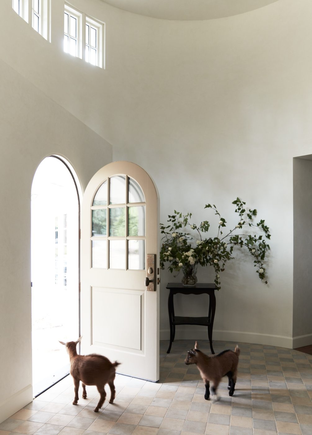 Interior of rounded double height foyer show arched front door of interior designer Molly Beth Kidd's Oregon home