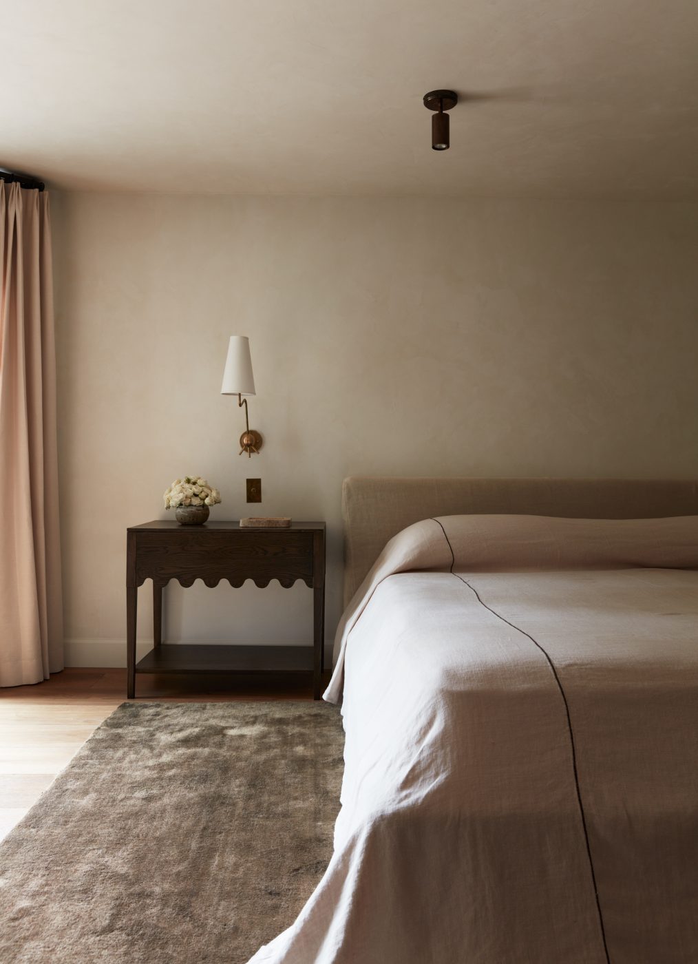 Linen draped bed and scalloped nightstand table in primary bedroom of interior designer Molly Beth Kidd's Oregon home