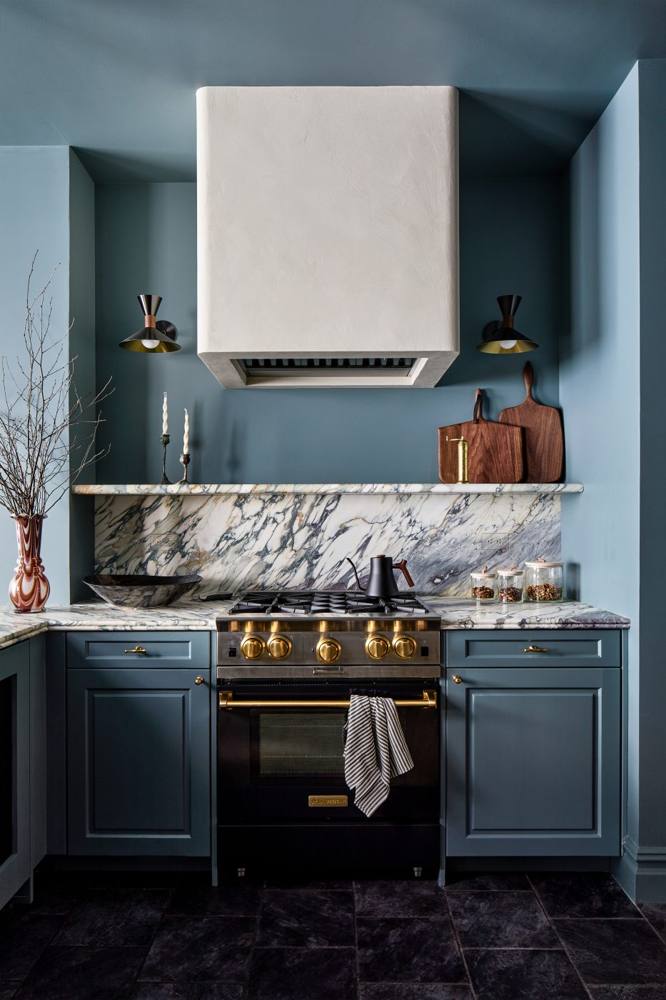 Range with plaster range hood above in blue-colored kitchen of Washington DC Georgetown penthouse apartment by interior designer Zoë Feldman