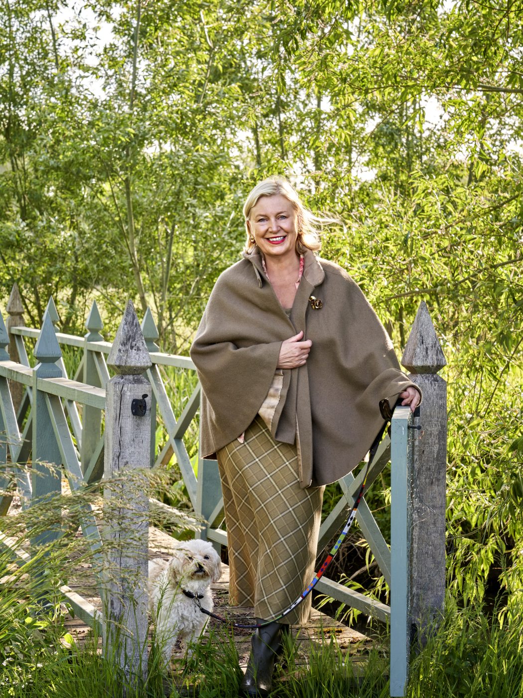 Portrait of Caryn Hibbert founder and designer of Thyme countryside hotel in England's Cotswolds pictured on a bridge in the estate's water meadow