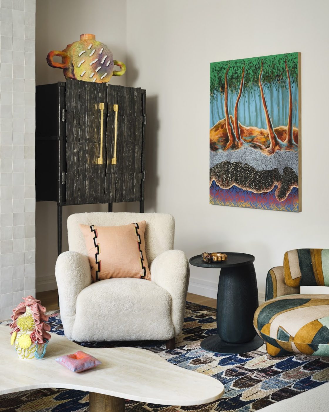 The living room of a Tribeca loft designed by Kati Curtis and featuring a lounge chair by Dagmar covered in plush sheepskin another by Royal Stranger upholstered in a graphic Lee Jofa linen; artwork by Didier Williams. a Jonatan Nilsson vessel, a Luke Proctor cabinet, and an Umberto Bellardi Ricci coffee table f