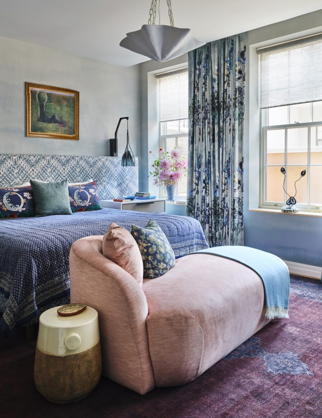 The primary bedroom in a Tribeca loft designed by Kati Curtis features Stephen Antonson pendant light, a custom bed, Ercole nightstands, a Verellen chaise upholstered in a Natasha Baradaran fabric, sconces by Holly Hunt, and artwork by Heidi Hahn.