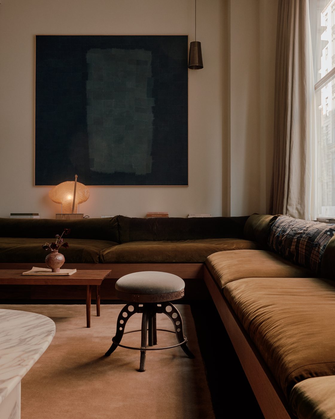 long low slung corner section sofa olive green velvet in living area of  Flatiron District loft in New York City Manhattan designed by Lauren Garrett's firm LP Creative