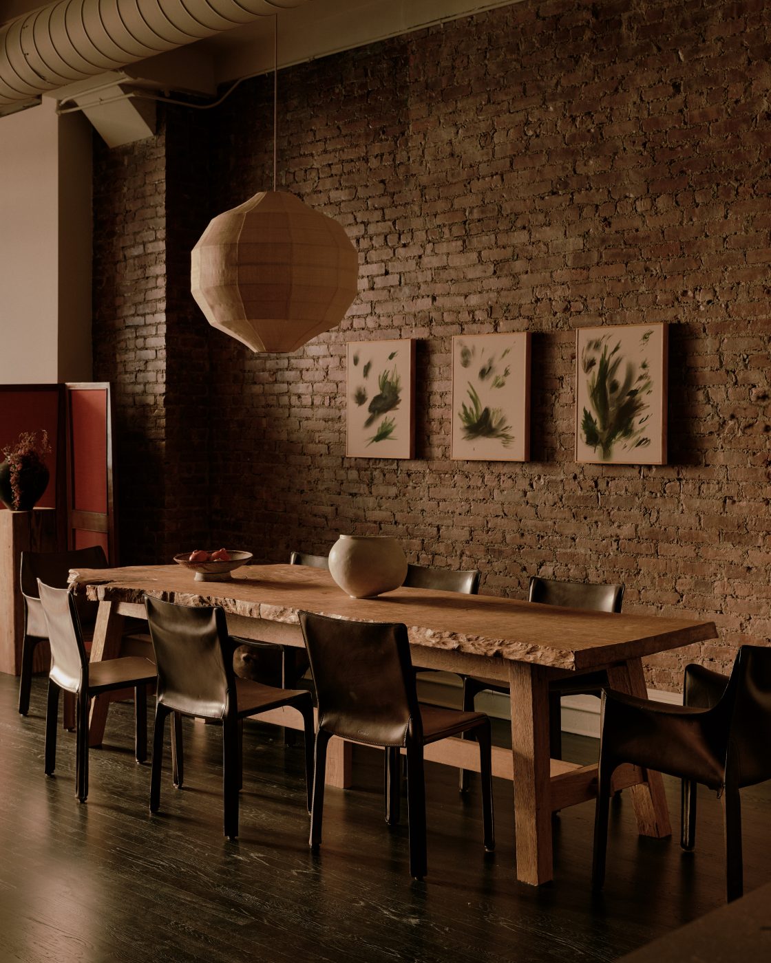 live-edge wood table and leather chairs in exposed-brick-walled dining area area of Flatiron District loft in New York City Manhattan designed by Lauren Garrett's firm LP Creative