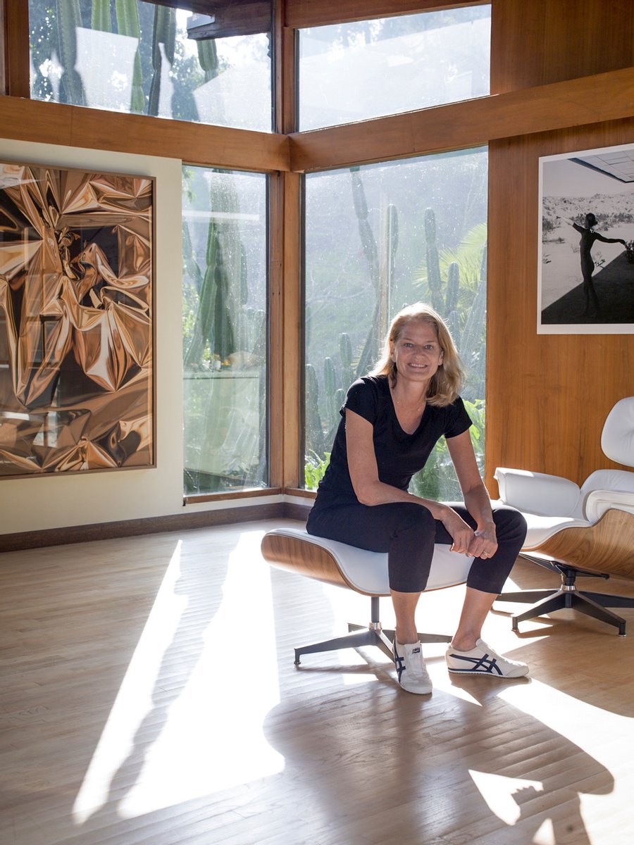 Photographer Mona Kuhn sits on an Eames lounge chair and ottoman amid works from her series "She Disappeared into Complete Silence."