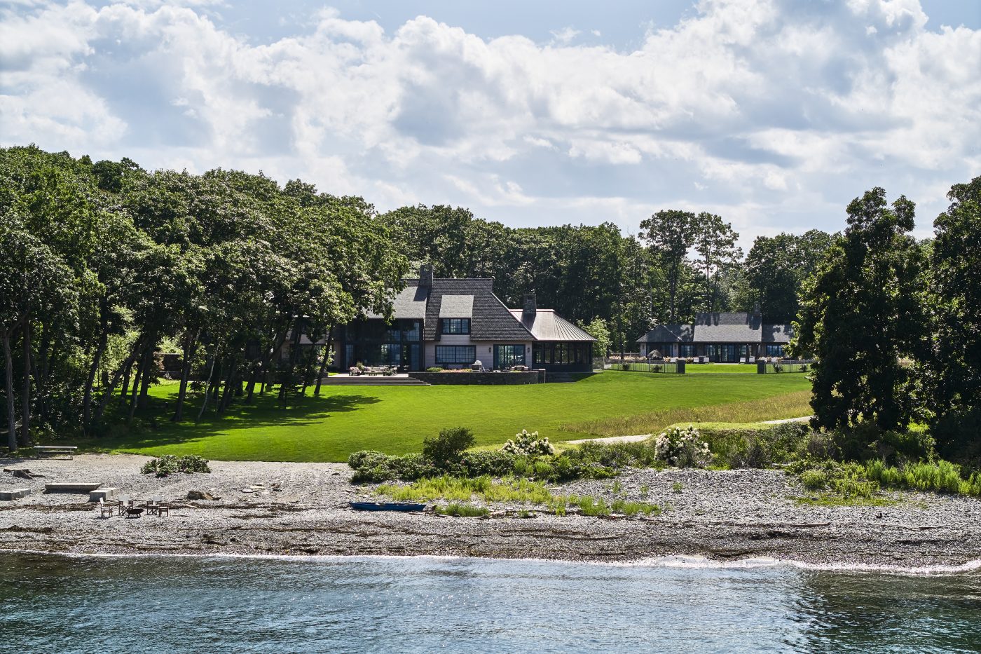 Exterior showing main house, pool house, lawn and rocky beach on water of a Maine coast home designed by Gray Davis and Will Meyer of the studio Meyer Davis