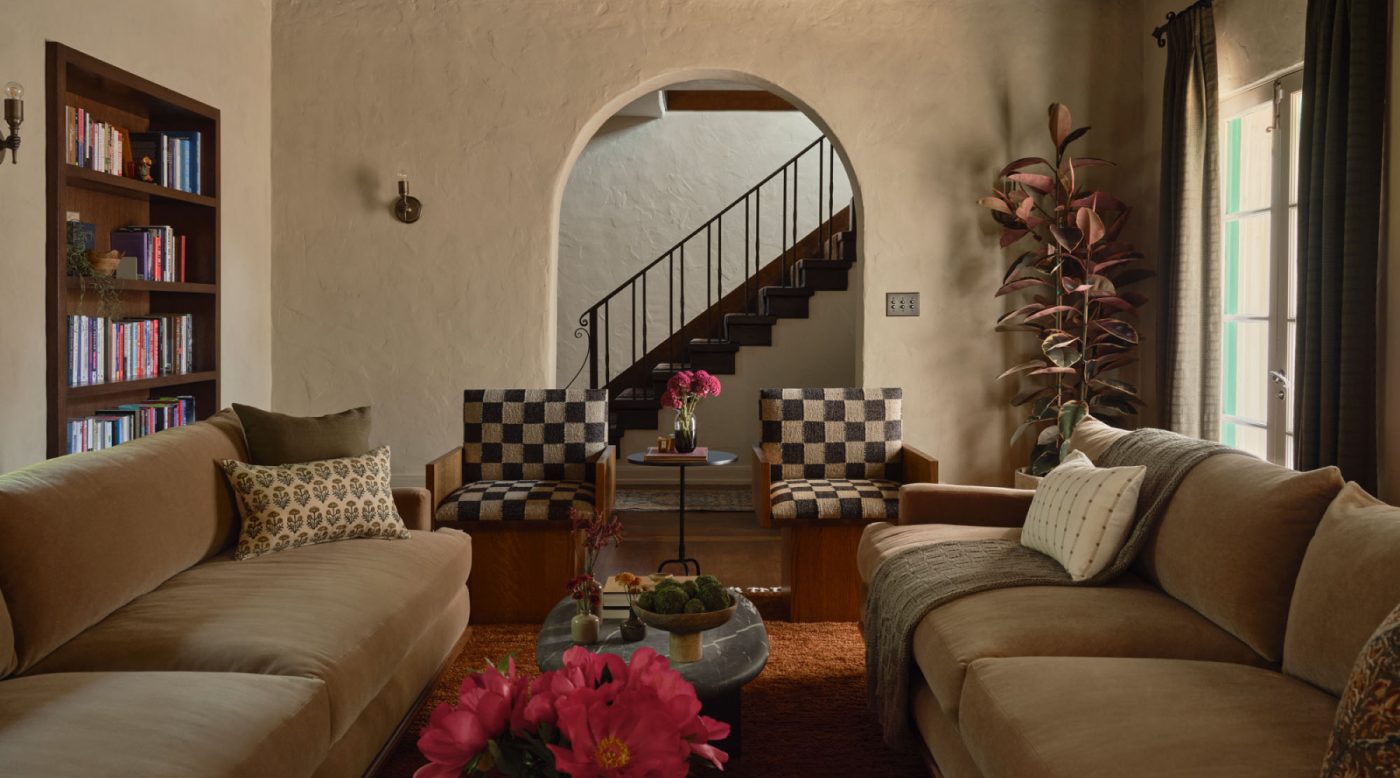 Living room with twin sofas flanking a series of marble coffee tables and pair of checkerboard print chair n front of arched opening to stairhall in Palo Alto Silicon Valley California Mediterranean house designed by Mandy Cheng