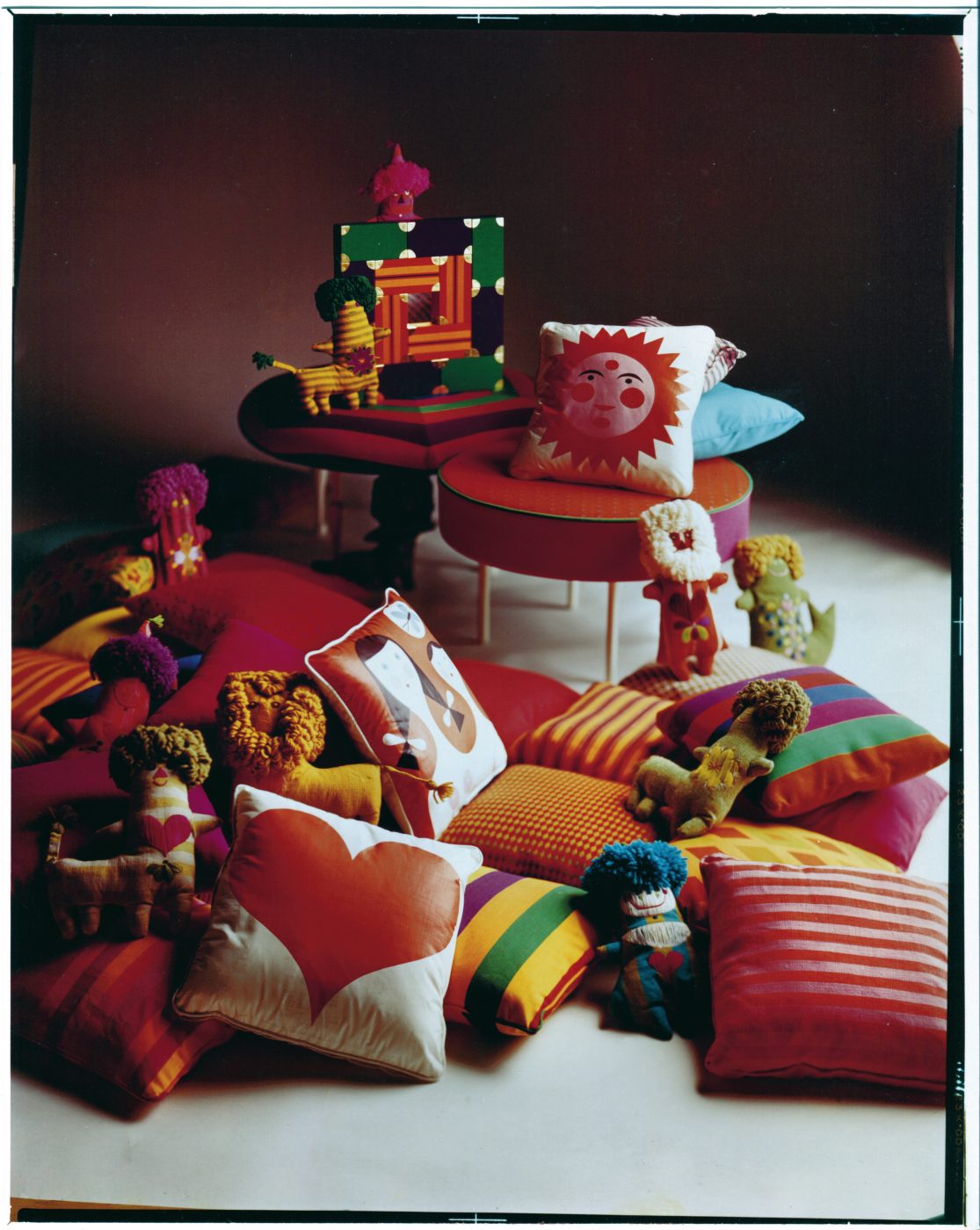 Patterned and brightly colored pillows and other designs by Alexander Girard alongside soft children's toys by Marilyn Neuhart