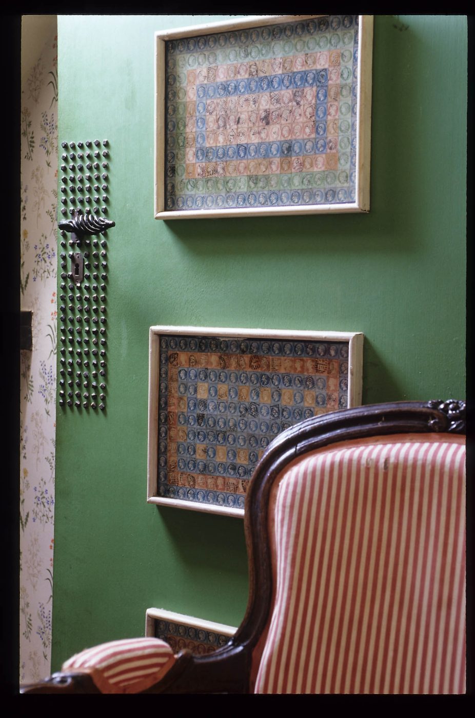 A framed stamp collage hung on the door of a guest bedroom in Jean Royère's home in Brittany