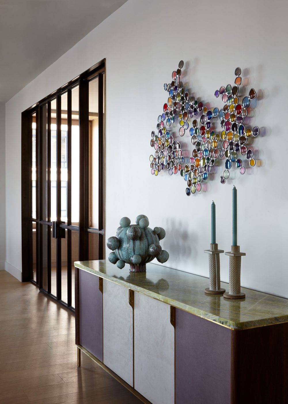 glazed-stoneware vase by Robbie Heidinger tops contemporary  credenza with artist Jim Lambie's Cool Breeze, made from dozens of eyeglass lenses, above.in Tribeca Manhattan New York loft designed by Damon Liss