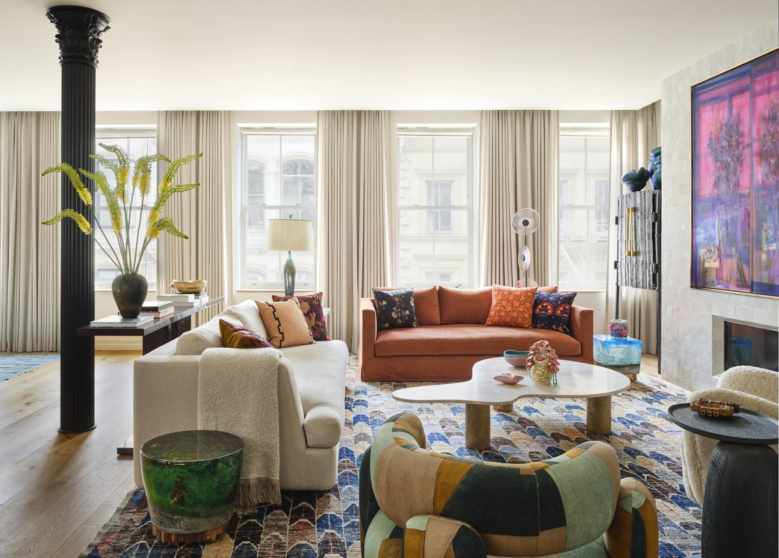 The living room of a Tribeca loft designed by Kati Curtis and featuring Dedar-upholstered sofas and a  illuminated, recycled-Murano-glass Hillsideout side table, from Galerie Philia, a vintage Moroccan rug and artwork by Ben Tong. 