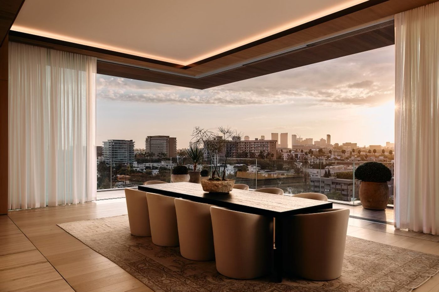 Dining area of penthouse in Los Angeles West Hollywood designed by Adair Lewis of JSN Studio with glass corner wall of glass opening to a balcony