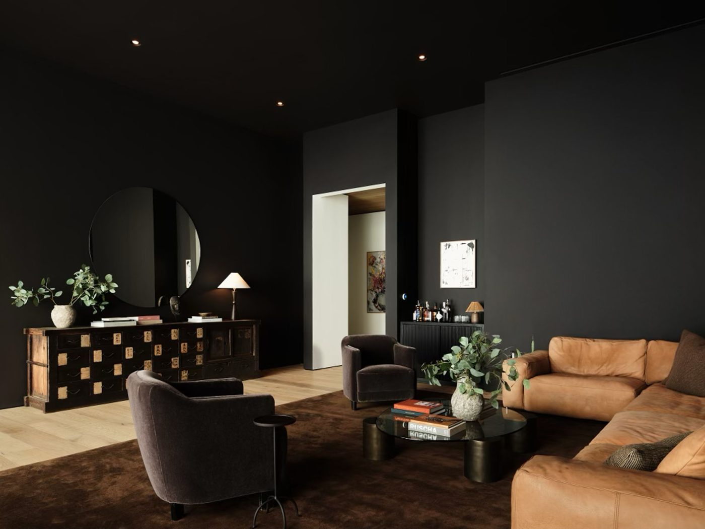 Den in penthouse in Los Angeles West Hollywood designed by Adair Lewis of JSN Studio furnished with The den features a leather sectional and pair of velvet-upholstered armchairs.