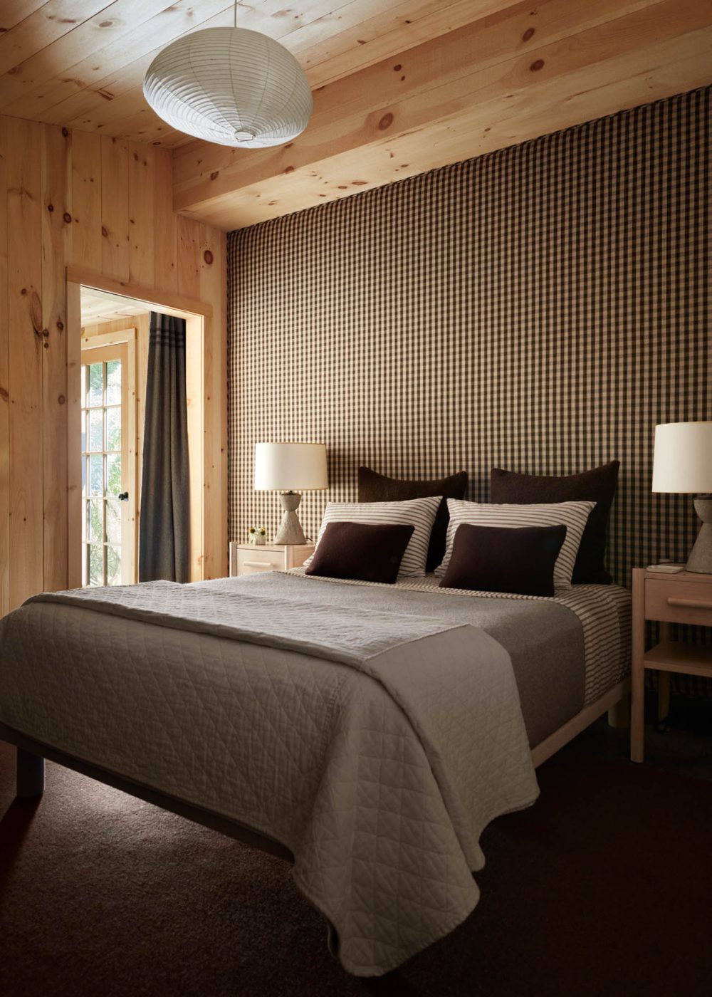 In the bedroom, a  chocolate-brown gingham linen by Holland & Sherry was used on an upholstered wall behind the bed.