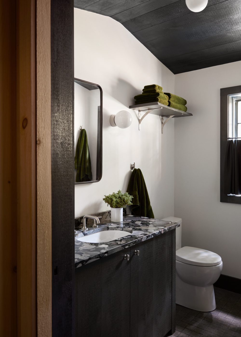 The powder room sports a forest green wood ceiling and handmade vanity.