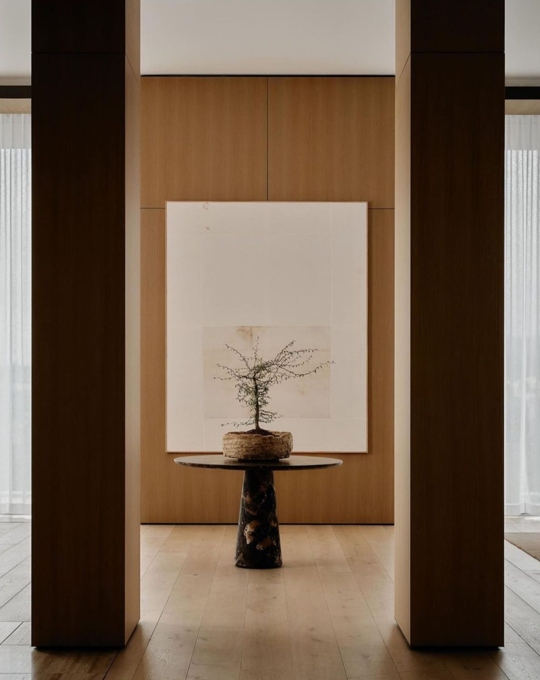 Entry of penthouse in Los Angeles West Hollywood designed by Adair Lewis of JSN Studio with bonsai tree in low clay vessel on black marble round pedestal table