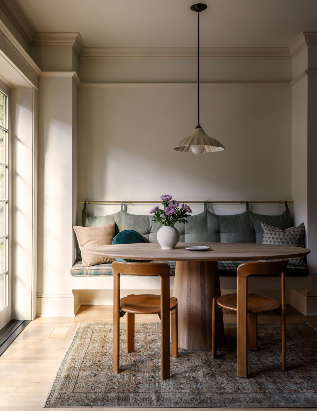 Breakfast nook with simple wooden oval table and mid-century chairs and banquette in a house in Seattle's Capitol Hill neighborhood designed by Lisa Staton