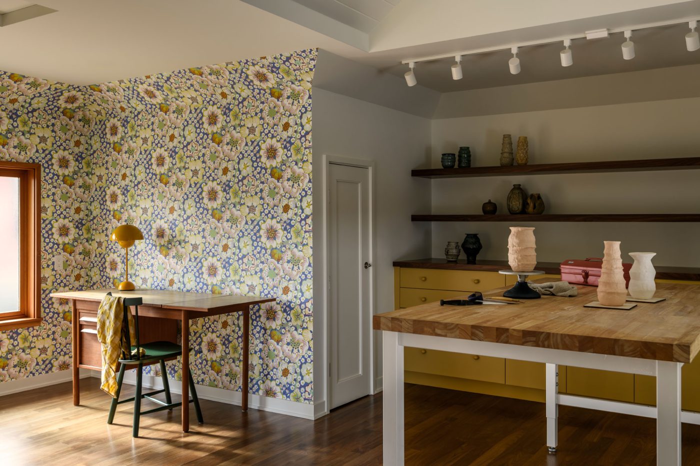 Pottery studio with yellow-painted lower cabinets, floral wallpaper and a mid-century desk in a house in Seattle's Capitol Hill neighborhood designed by Lisa Staton