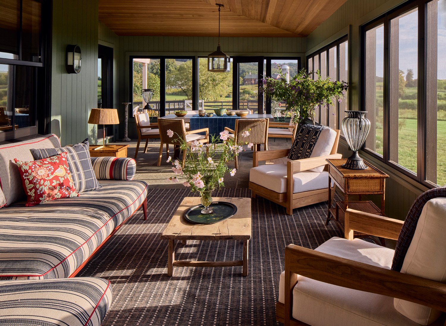 In the sun porch, a striped B&B Italia sectional, Perennials and Sutherland chairs are joined by vintage rattan side tables
