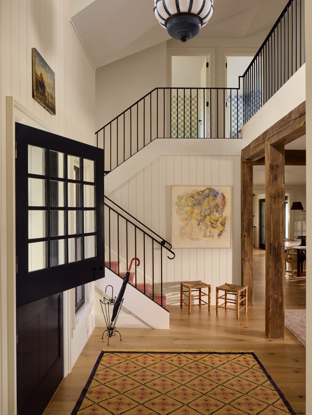 In the entry are vintage mid-century stools and a French umbrella stand, along with wrought-iron railings open up the space.