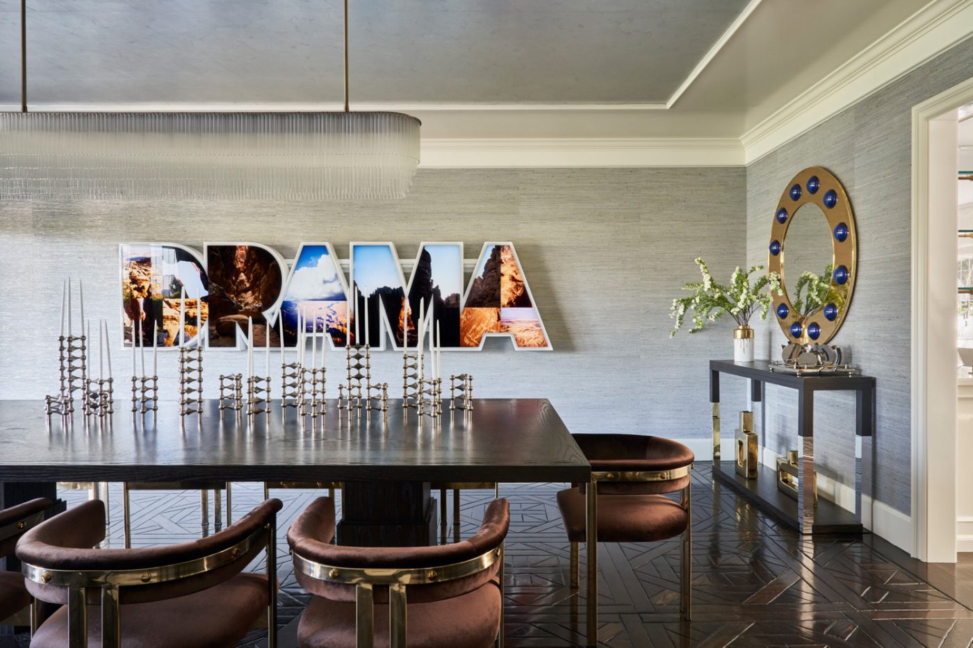 In the dining room, a vintage table is surrounded by brass chairs upholstered in chocolate velvet.