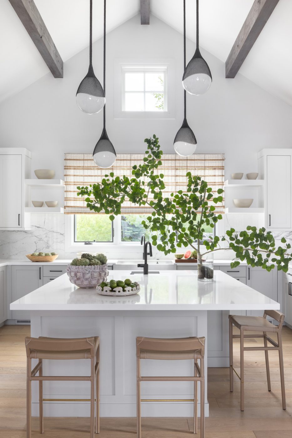 All white Kitchen with light wood floors and black hardware and big windows in a ranch house with interiors designed by Valerie Peña in Jackson Hole Wyoming