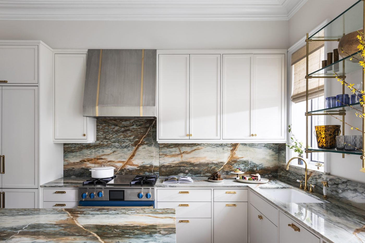 In the kitchen, eye-catching countertops and backsplashes in multihued marble with painterly copper-colored accents pop against the minimal white cabinetry