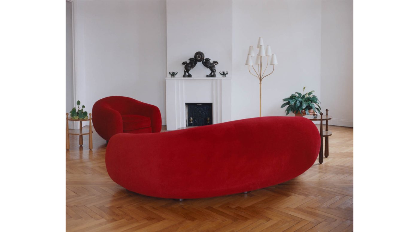 A pair of Quille tables, a red Polar Bear armchair and sofa, and a Persane floor lamp, all by Jean Royère, in the Royère showroom in Paris