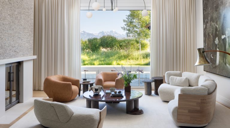 A pair of Pierre Yovanovitch Asymmetry chairs, an Ian Felton Mullunu lava-stone table and a Michael Anastassiades chandelier from Friedman Benda in the neutrally toned living room of a ranch house with interiors designed by Valerie Peña in Jackson Hole Wyoming