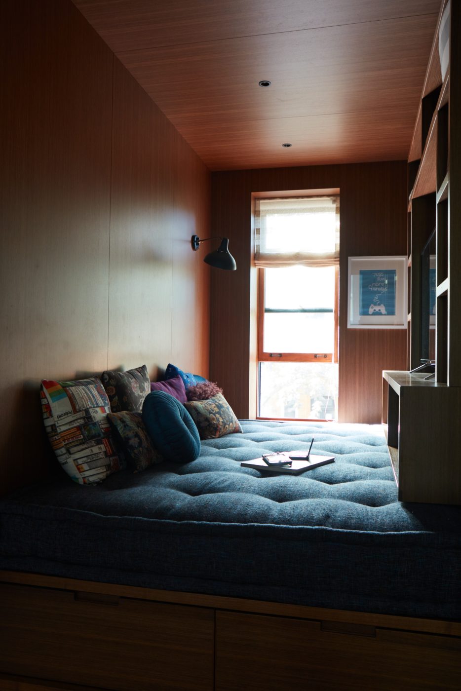 Outside the boys’ rooms, the designers converted the small space at the end of the stair hall into a snug entertainment den, where a plush daybed arrayed with cushions tucks into the walnut-paneled alcove along with cabinets for a TV and gaming equipment.