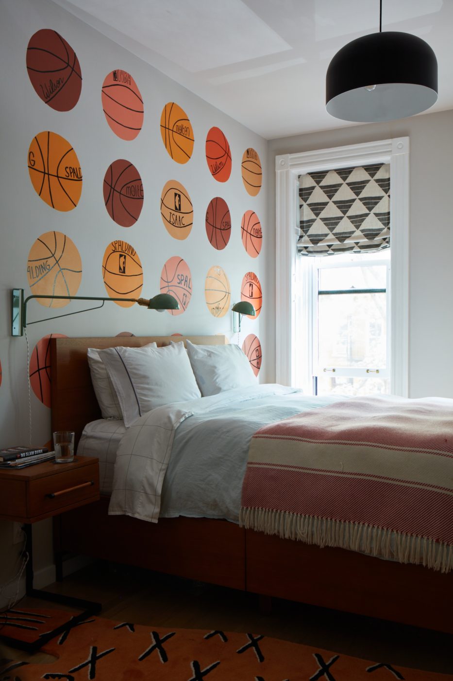One of the son's have a mural of basketballs behind his bed.