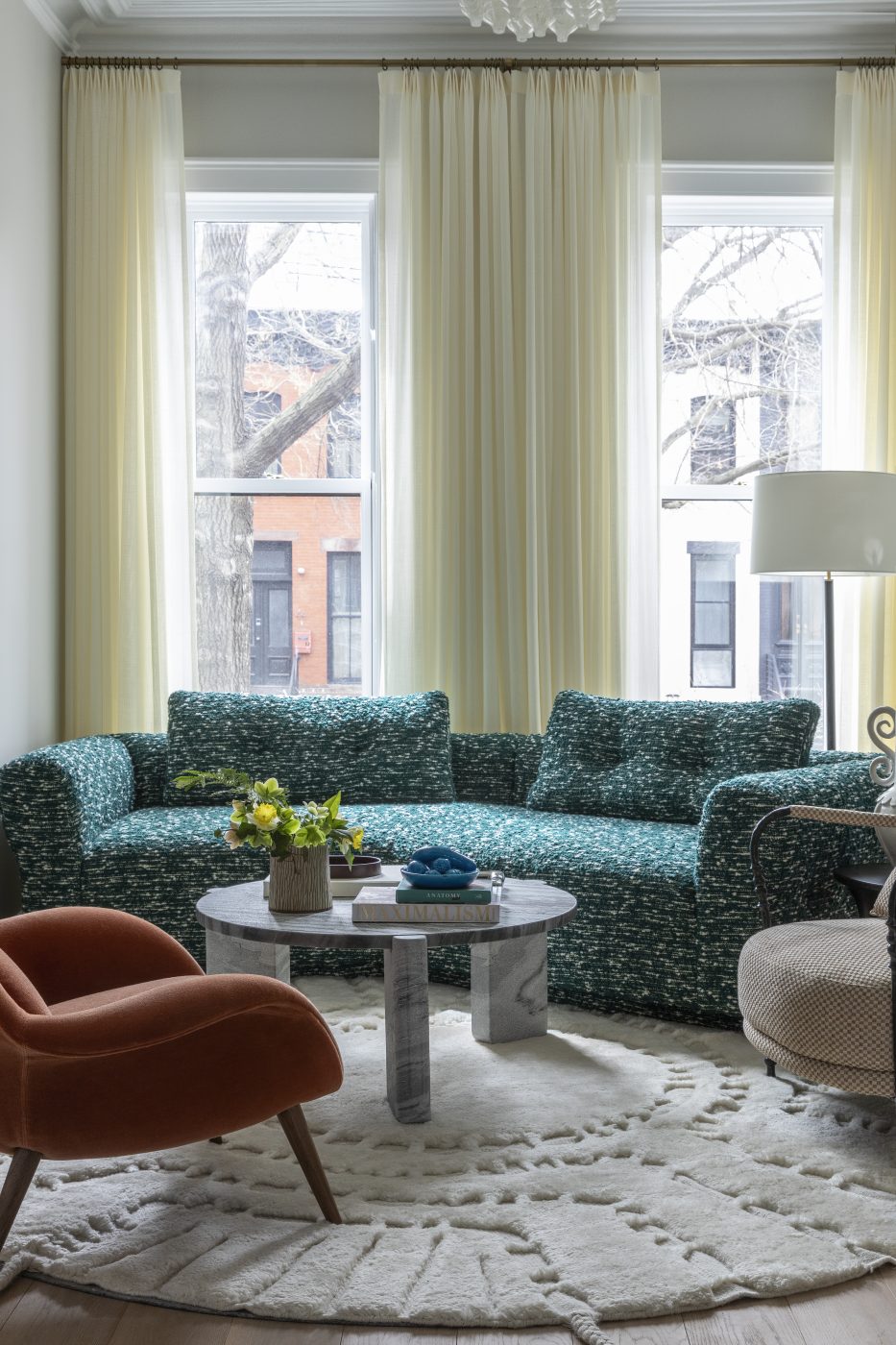 In the front salon, a custom-designed sofa curves around a stone coffee table, joined by a mohair lounge chair by Space Copenhagen, while a 1960s Kalmar Tulipan chandelier adds vintage verve above.