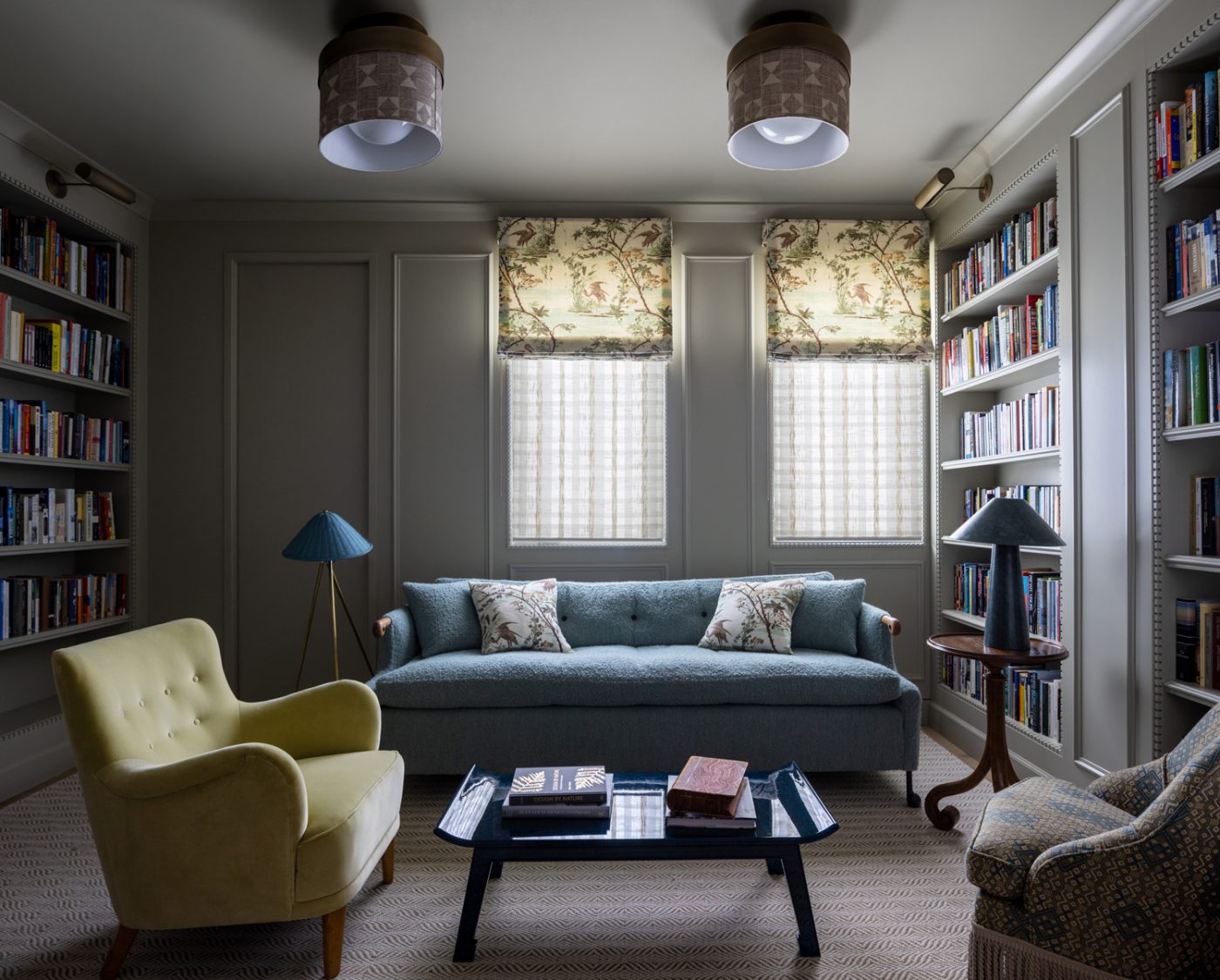 Library of a San Francisco row house designed by Marea Clark featuring a Nickey Kehoe chair across a lacquered coffee table from a custom BDDW sofa accented by throw pillows covered in a botanical print that matches the roman shades.