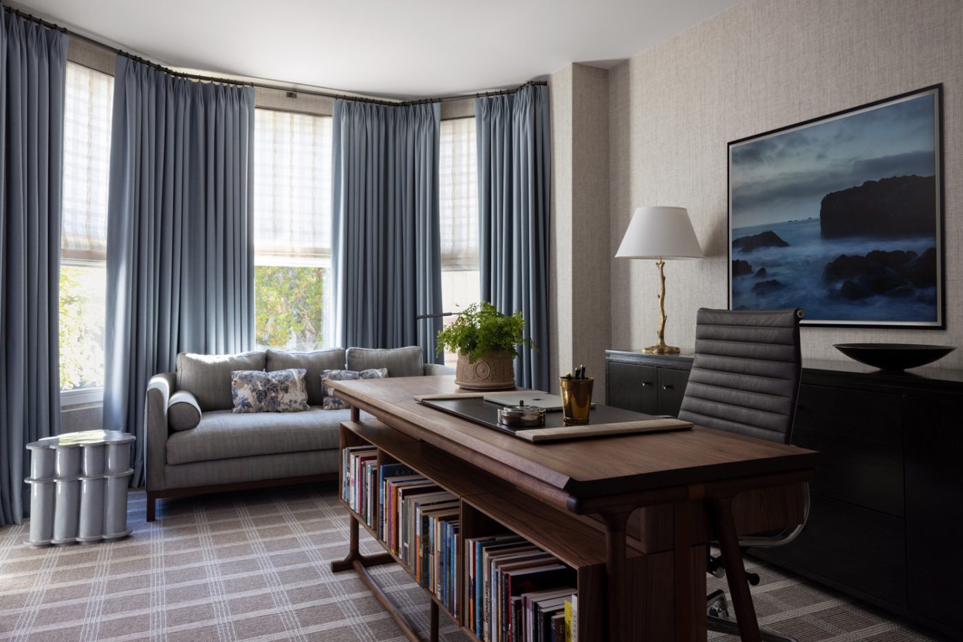 Office of a San Francisco row house designed by Marea Clark featuring an oak desk by San Francisco–based furniture studio Ted Boerner, behind which is a Charles and Ray Eames for Herman Miller office chair. In front of the bay window is a custom sofa from Lawson-Fenning.