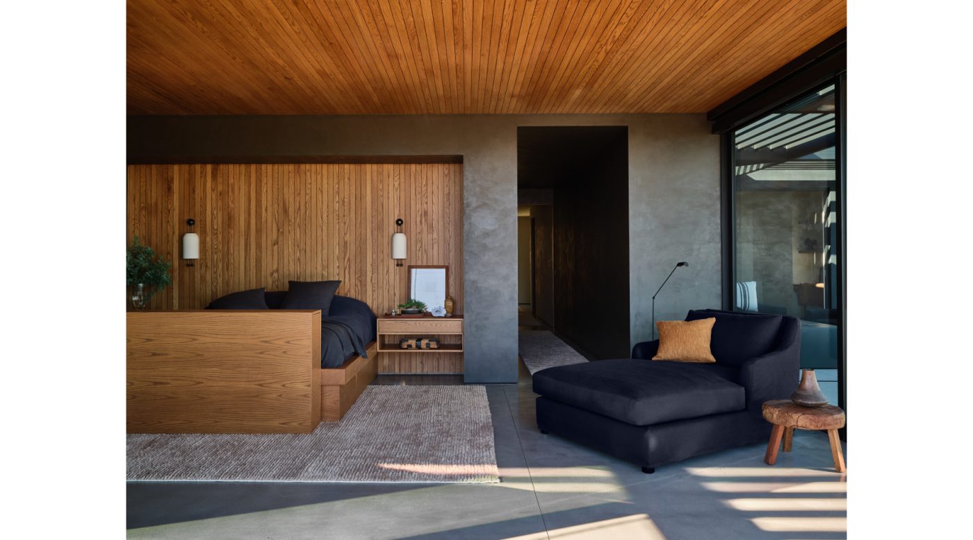 Primary bedroom in Malibu California home of NFL player Baltimore Ravens Ronnie Stanley designed by Sarah Solis featuring a bed built into oak-paneled wall and a large lounge chair chaise
