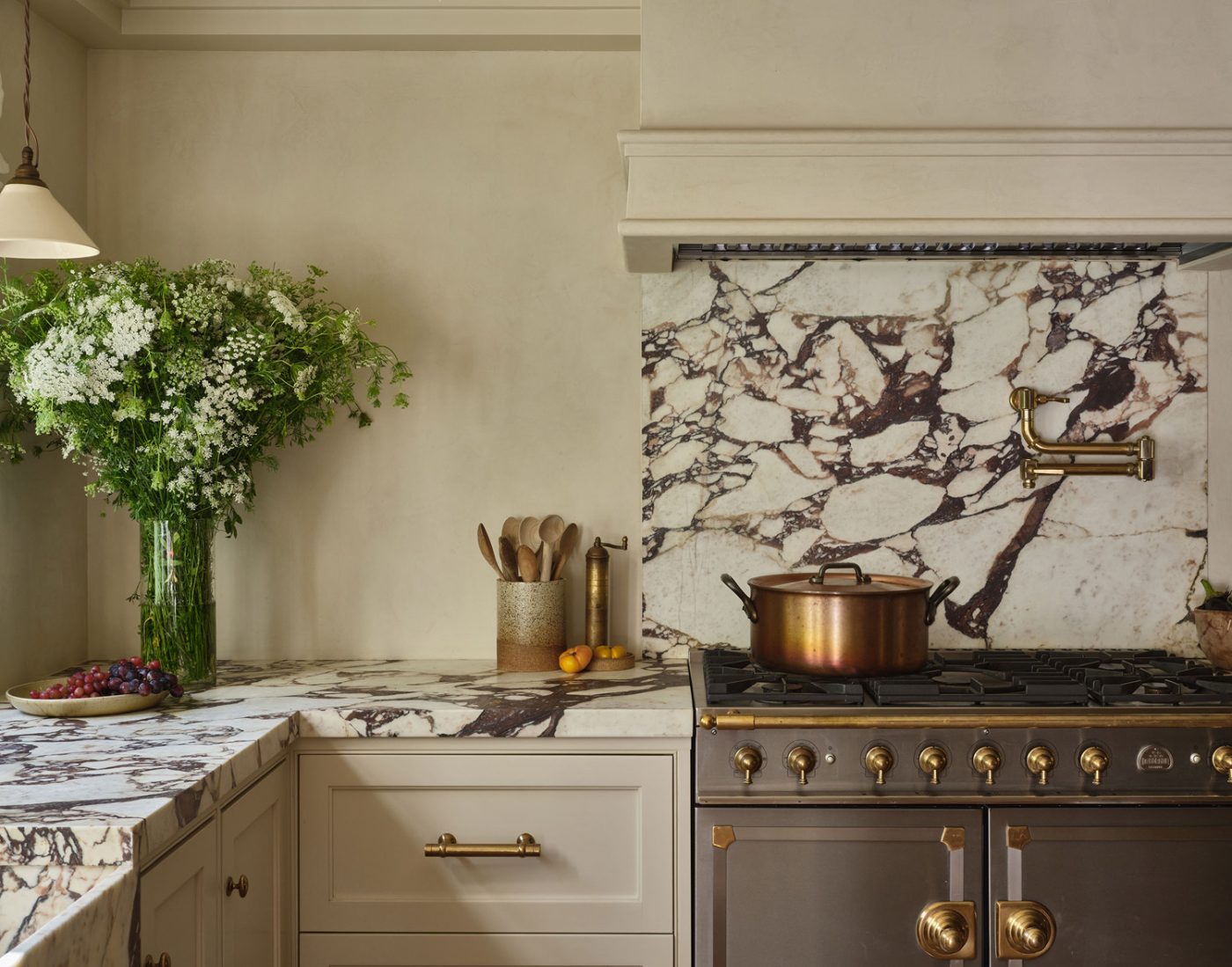 Kitchen of Malibu California home of interior designer Sarah Solis featuring Calacatta Viola marble for the counters and backsplash and  Le Cornue range under plaster hood