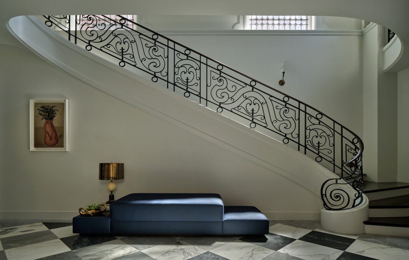 Black-and-white checkerboard stair hall with base of sweeping staircase in Edwardian house in San Francisco's Pacific Heights with interiors by Brittany Giannone's ABD STUDIO