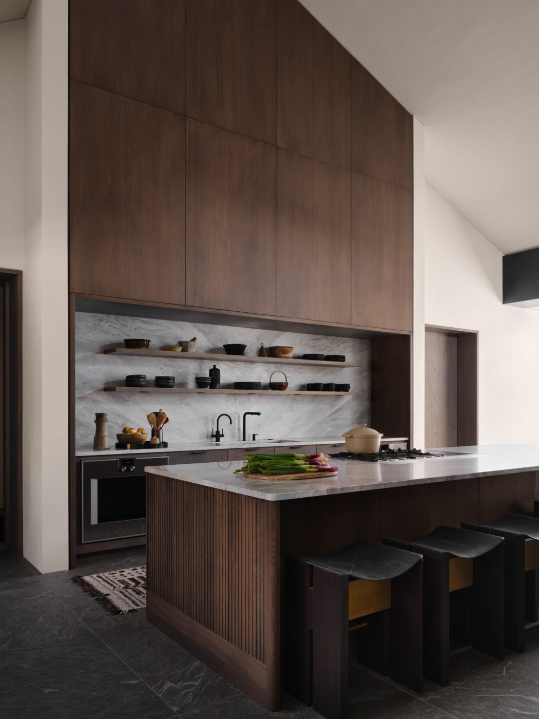 kitchen of a house designed by Vanessa Alexander in Aspen, Colorado, featuring dark wood cabinets, light gray marble counters and backsplash and white walls