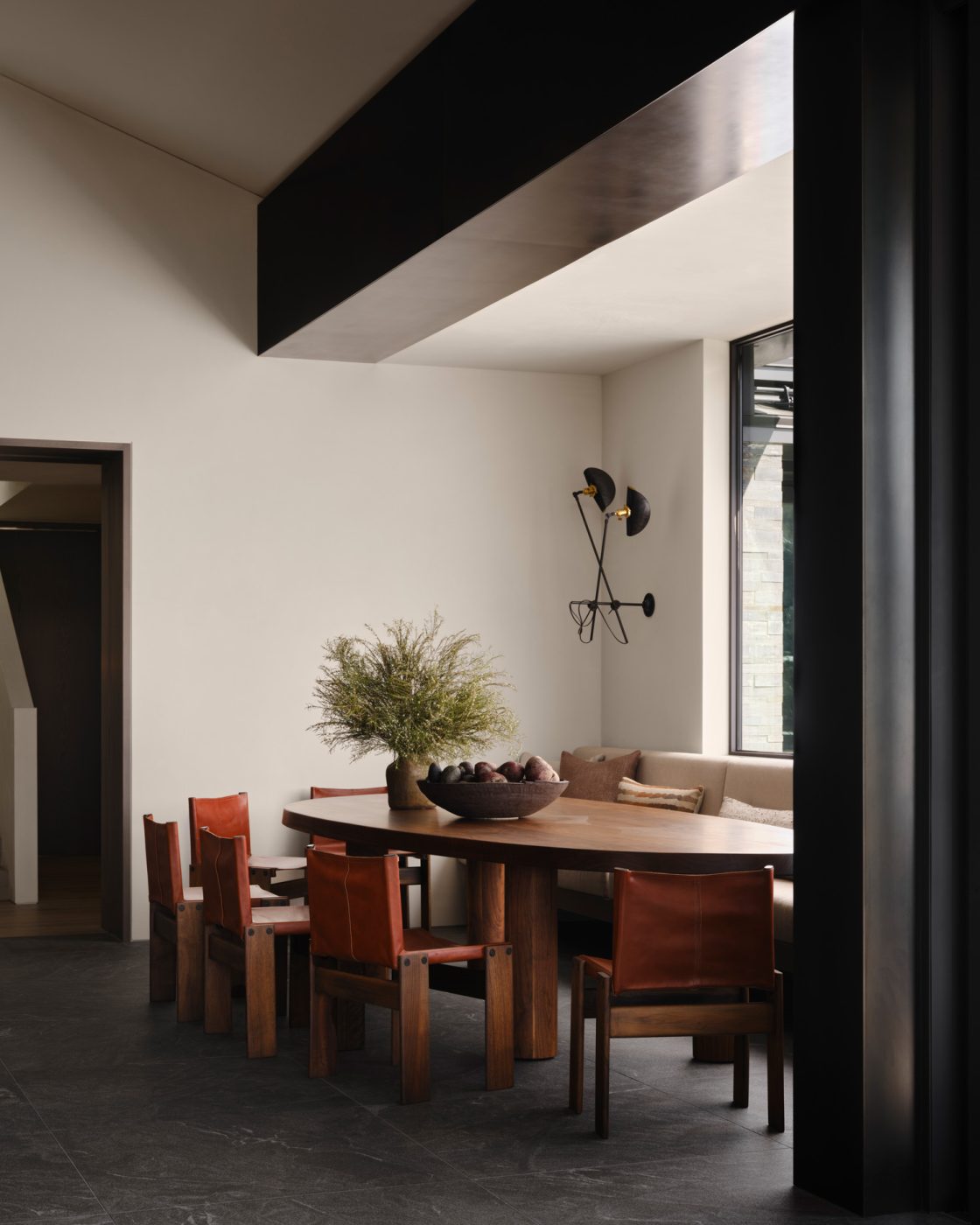 breakfast nook of kitchen of a house designed by Vanessa Alexander in Aspen, Colorado, featuring Carlo Scarpa Monk chairs  with leather seats and backs sit at an oval wood custom table
