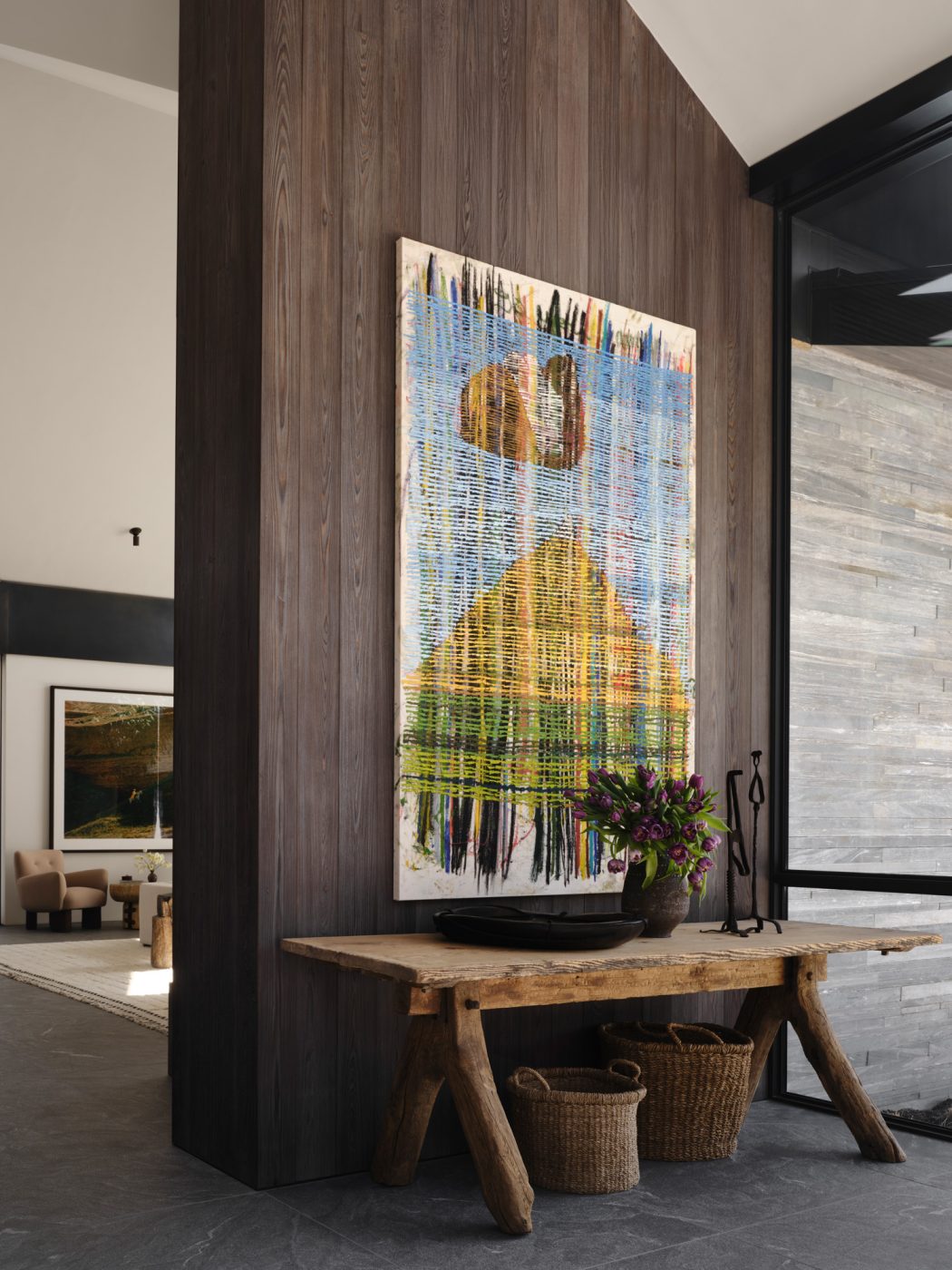 living room of a house designed by Vanessa Alexander in Aspen, Colorado, featuring shou sugi ban charred-wood siding, rustic Swedish bench with baskets underneath and woven art above