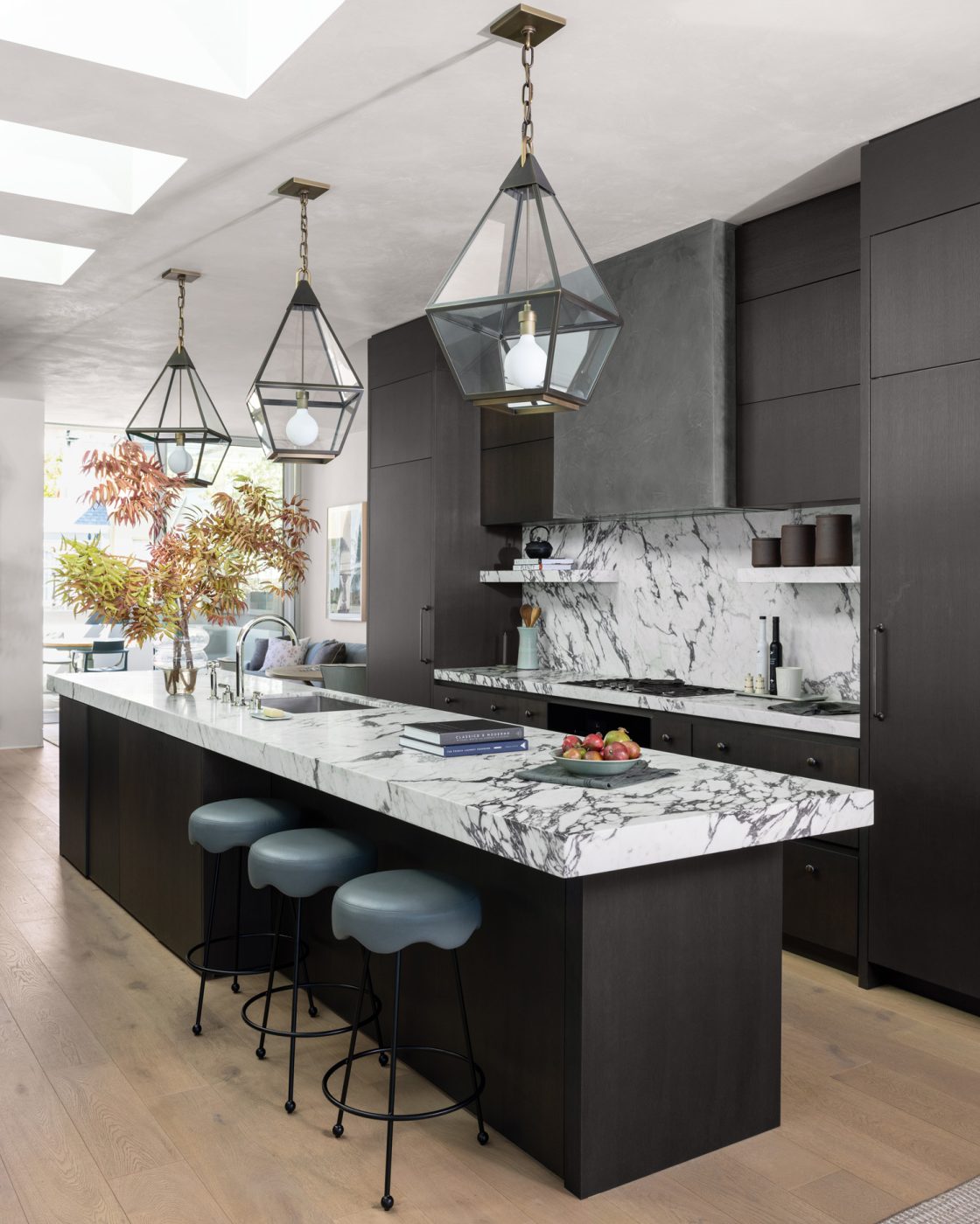 Kitchen of a San Francisco row house designed by Marea Clark featuring iron counter stools, Urban Electric lantern-style pendants and Calacatta Viola marble counters and backsplash