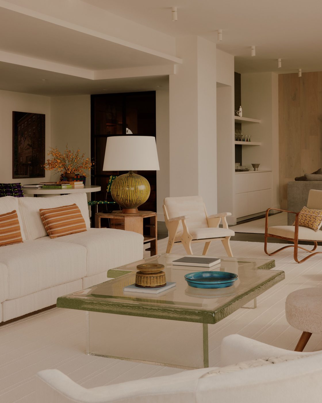 Living room in nearly all white minimalist loft apartment in New York's West Village  designed by Clive Lonstein and featuring Jacques Adnet armchairs, a cast-glass coffee table from Lonstein's new furniture collectio and a large ceramic table lamp attributed to the Swedish maker Rörstrand